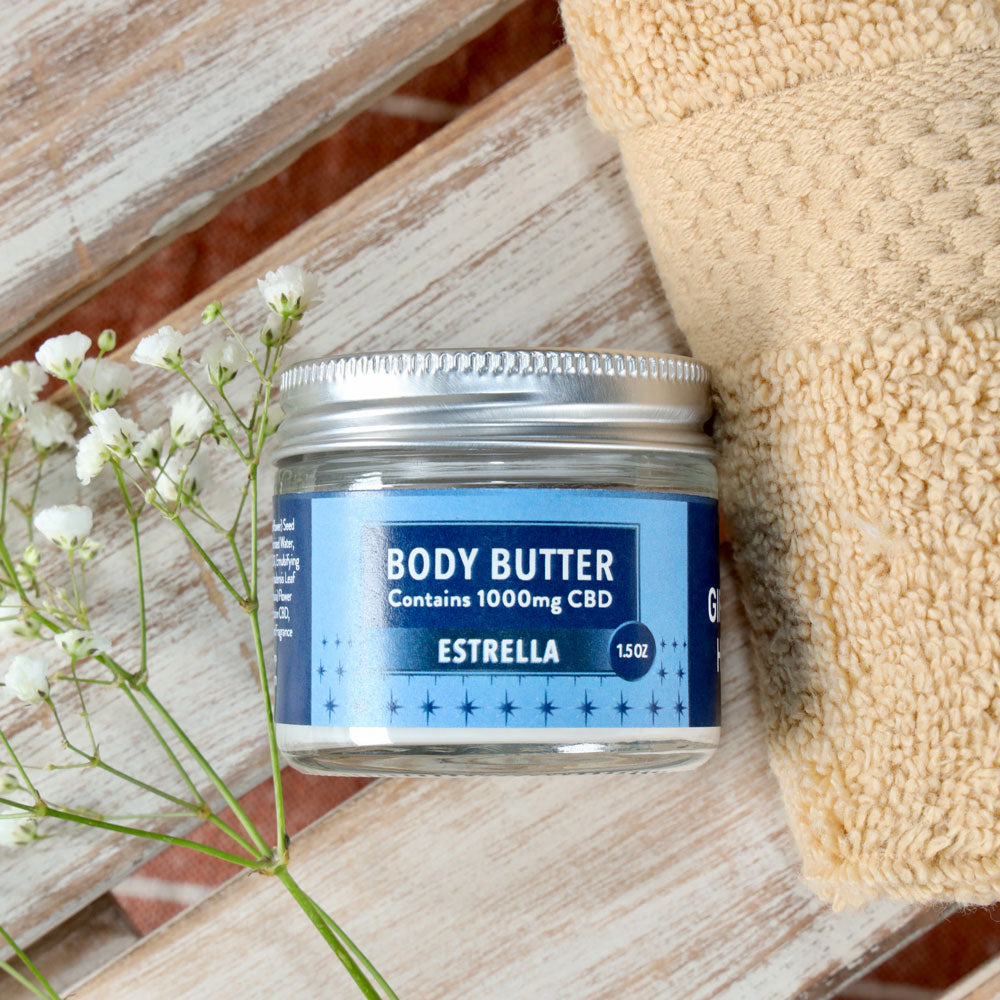 Jar of Body Butter - Estrella shown on a wooden surface with spa items