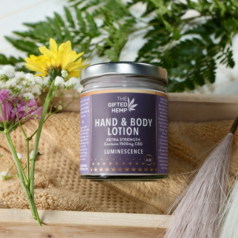 Jar of Hand & Body Lotion Estrella on a towel inside a wood box with flowers and spa elements around it