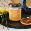 Jar of Hand & Body Lotion Solstice on a wooden board with flowers and citrus elements around it