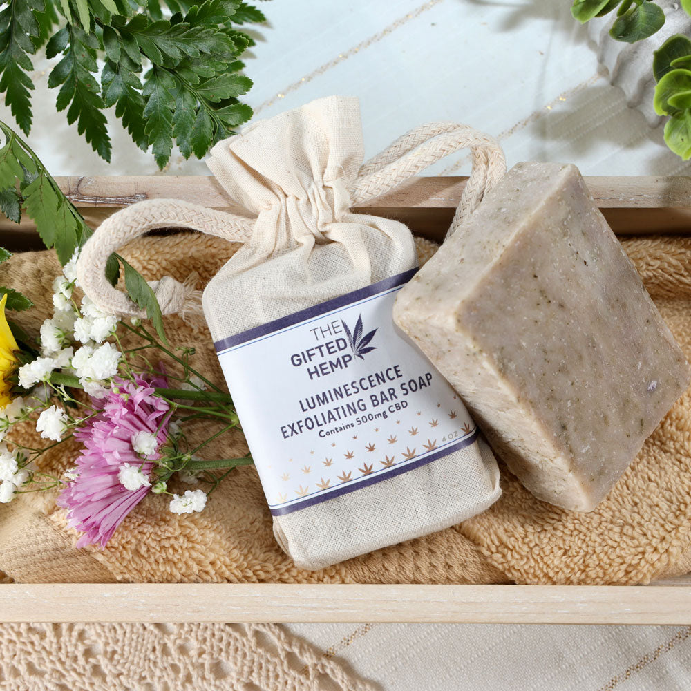 Bar of Exfoliating Soap - Luminescence wrapped in a canvas bag sitting on a towel in a wooden box