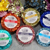 Six colorful wrapped shower steamers from The Gifted Hemp in various scents displayed with fresh flowers